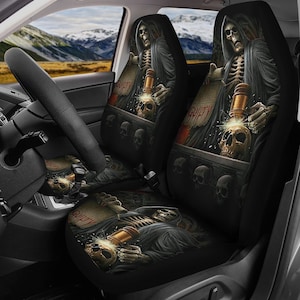 May include: Two black car seat covers with a graphic of a skeleton holding a gavel and a scroll that says "Guilty". The skeleton is wearing a black robe and has a skull on its head. The background is black with skulls and flames.