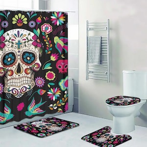 Puede incluir: Un conjunto de ba&ntilde;o con una cortina de ducha negra con un dise&ntilde;o de calavera de az&uacute;car colorida, una tapa de asiento de inodoro a juego y dos alfombras de ba&ntilde;o. La cortina de ducha tiene un patr&oacute;n floral con p&aacute;jaros y calaveras.