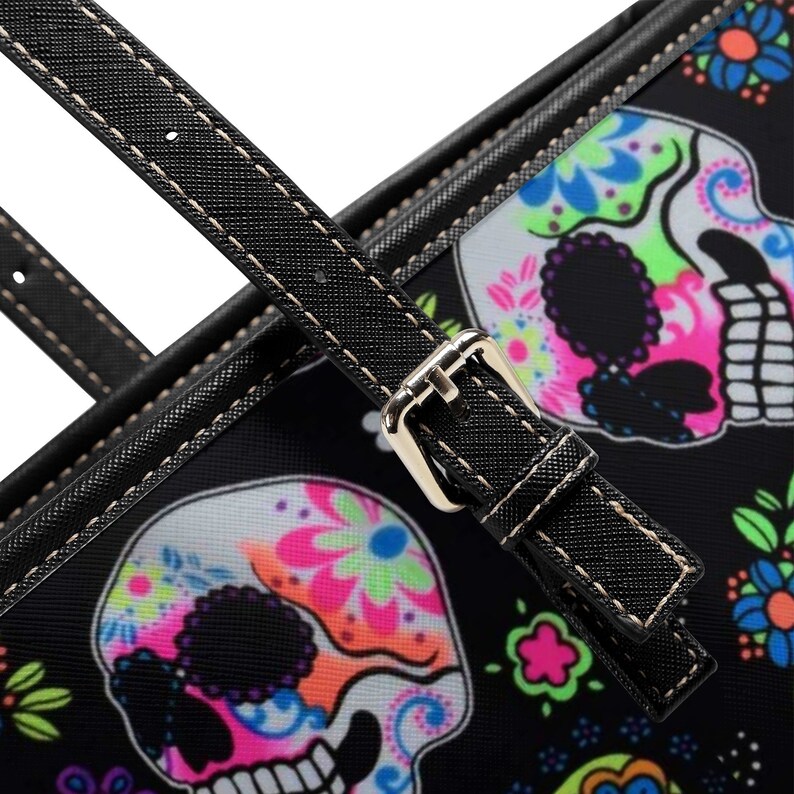 May include: Black tote bag with a colorful sugar skull design. The bag has a black strap with a silver buckle.