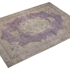 K&ouml;nnte beinhalten: Ein Vintage-Teppich mit einem verblassten Farbton in Lila und Beige. Der Teppich hat ein zentrales Medaillon-Design mit komplizierten Blumenmustern.