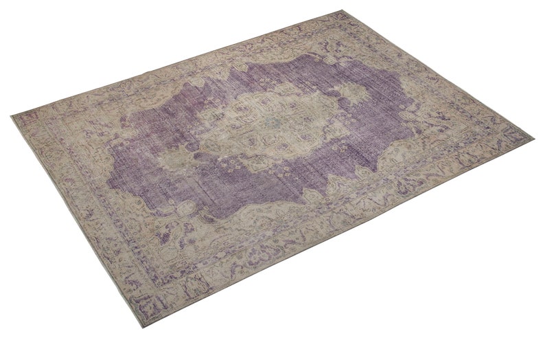 K&ouml;nnte beinhalten: Ein Vintage-Teppich mit einem verblassten Farbton in Lila und Beige. Der Teppich hat ein zentrales Medaillon-Design mit komplizierten Blumenmustern.