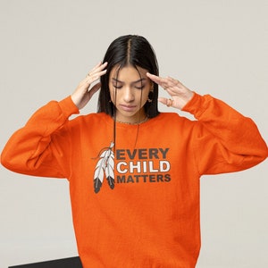 May include: Orange sweatshirt with the text "Every Child Matters" and a graphic of two feathers.