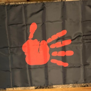 May include: A black flag with a red handprint in the centre.