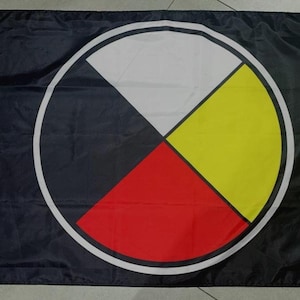 May include: A rectangular flag featuring a black background with a large central circle divided into four equal quadrants. The quadrants are coloured white, yellow, red, and black, enclosed within a thick white circular border and two metal grommets.