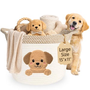 May include: A large, white rope basket with a brown and cream striped rim, filled with a plush dog toy, bone-shaped toy, and a cream-colored blanket. A tag reads "Large Size 15"x11". A golden retriever puppy is next to the basket.