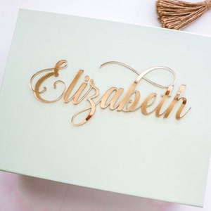 May include: A light green box with a gold mirror-like nameplate that reads "Elizabeth".