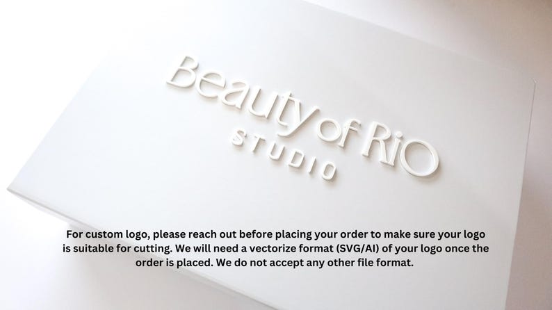 Może przedstawiać: Białe pudełko z nadrukowanym tekstem "Beauty of Rio Studio" na g&oacute;rze. Pudełko zawiera r&oacute;wnież instrukcje dotyczące zam&oacute;wień niestandardowych logo, wskazując, że do cięcia wymagany jest format wektorowy (SVG/AI).