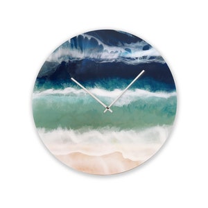 Puede incluir: Un reloj de pared redondo con un diseño abstracto de una ola de océano en azul, verde y blanco. Las manecillas del reloj son plateadas.