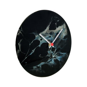 Puede incluir: Un reloj de arte abstracto en blanco y negro con manecillas blancas y una manecilla de segundos roja.