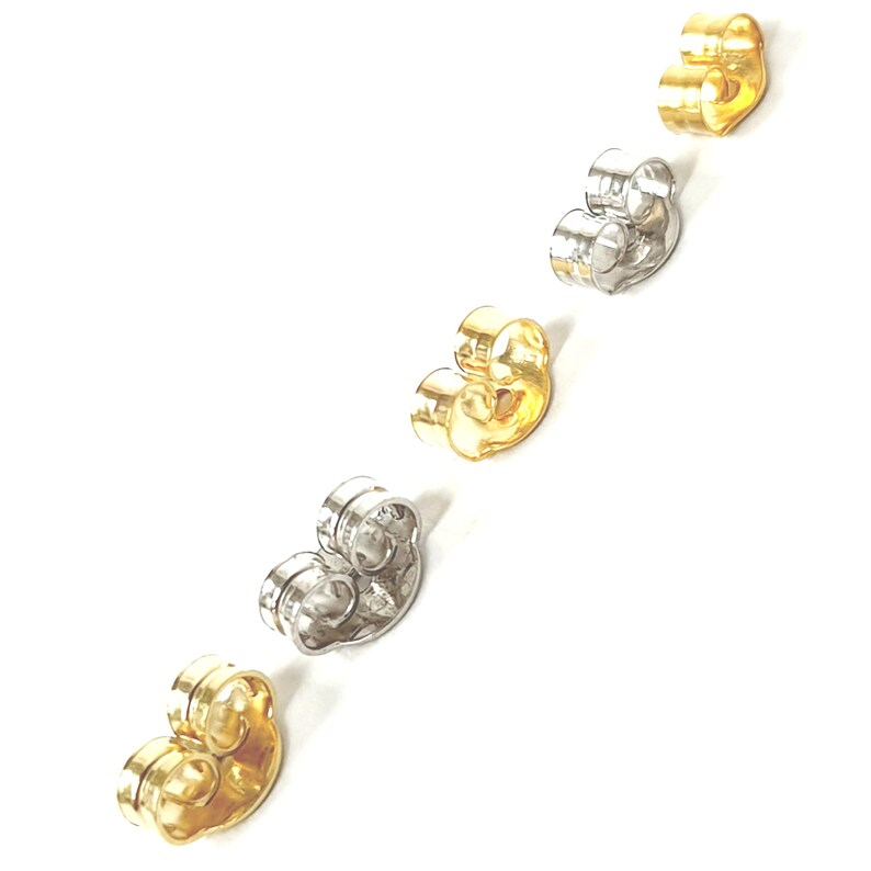May include: Five earring backs in different colors: gold, silver, and two shades of gold. The backs are made of metal and have a curved shape.