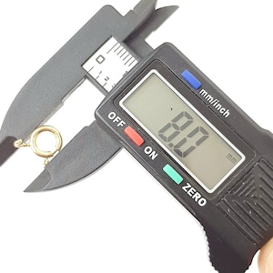 May include: A close-up of a digital caliper measuring a gold-colored jump ring. The caliper reads 8.0 mm.