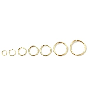 May include: A set of seven gold jump rings of varying sizes. The rings are arranged in order of size, with the smallest ring on the left and the largest ring on the right.