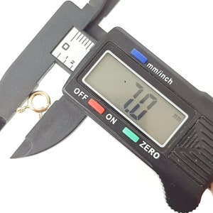 May include: A close-up of a digital caliper measuring a gold-colored jump ring. The caliper reads 7.00 mm.