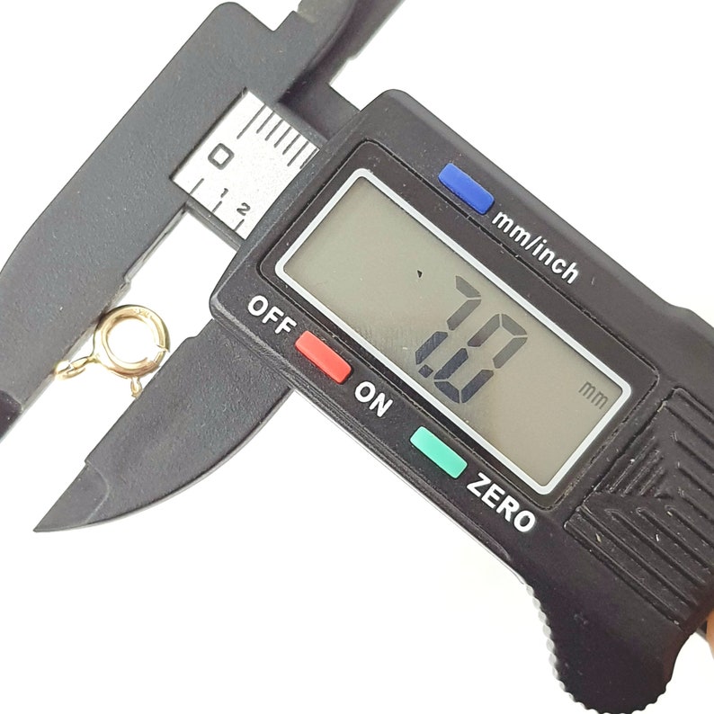May include: A close-up of a digital caliper measuring a gold-colored jump ring. The caliper reads 7.00 mm.
