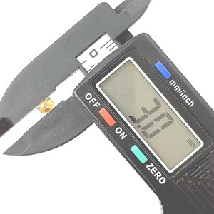 May include: A black digital caliper measuring a small gold object. The display reads "1.0" mm.