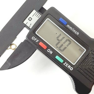May include: A black digital caliper with a display showing 4.0 mm. The caliper is used to measure the size of an object.