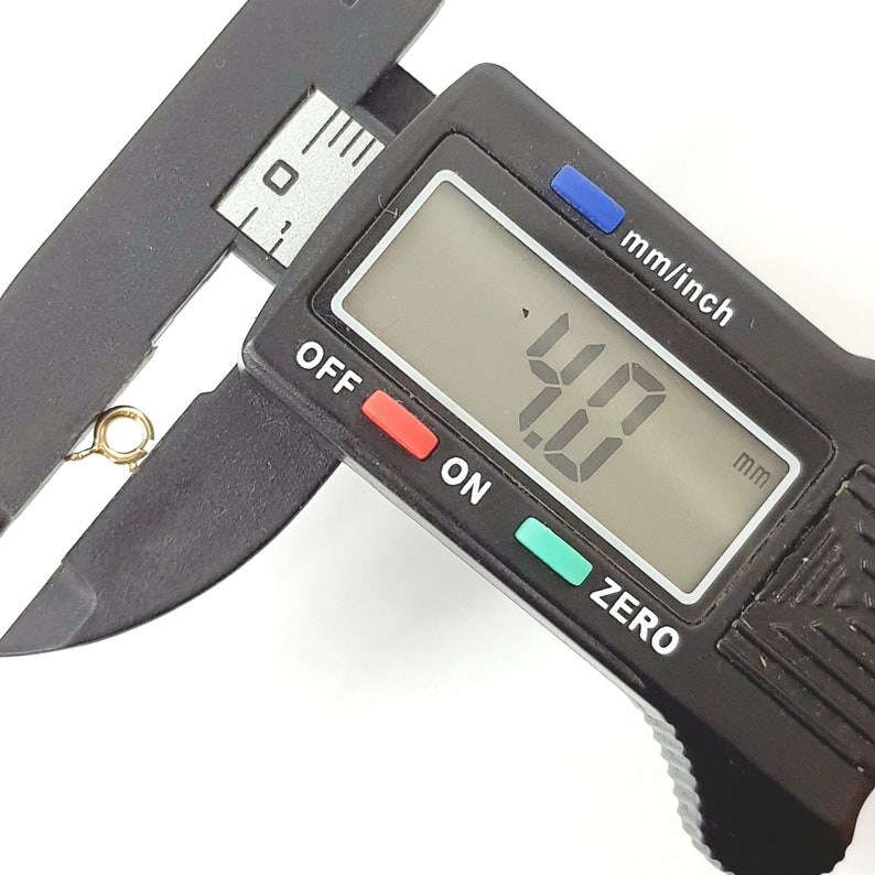 May include: A black digital caliper with a display showing 4.0 mm. The caliper is used to measure the size of an object.
