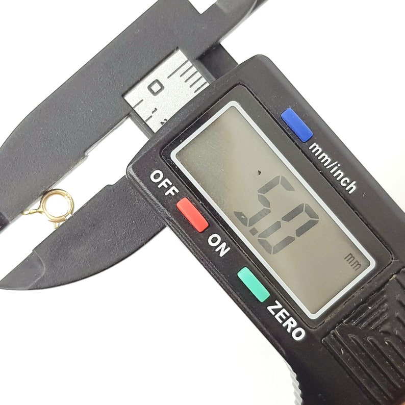 May include: A close-up of a digital caliper measuring 5.0 mm. The caliper is black with a digital display and buttons labeled "OFF", "ON", and "ZERO".