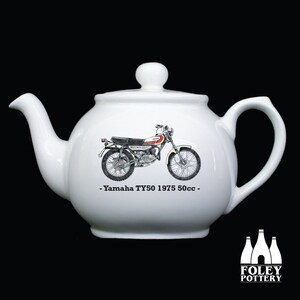 Könnte beinhalten: Weiße Teekanne aus Keramik mit einer Schwarzweißillustration eines Yamaha TY50 Motorrads. Der Text "Yamaha TY50 1975 50cc" ist auf die Teekanne gedruckt.