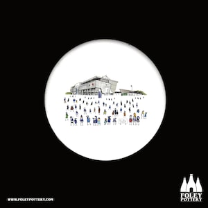 May include: A white ceramic coaster featuring a black and white illustration of a stadium with a crowd of people in front of it. The text "All Bull No Walsh" is on a sign held by one of the people in the crowd.