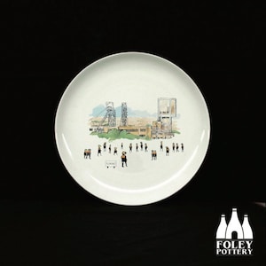 May include: White ceramic plate with a black and white illustration of a mining town with a group of people standing in front of it. The plate has the word "Florence" written on it.