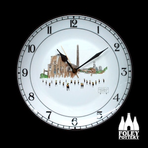 May include: Round white ceramic wall clock with black numerals and hands. The clock face displays a factory scene illustration and the text "CHATTERLEY WHITTIELD". A decorative item for the home.