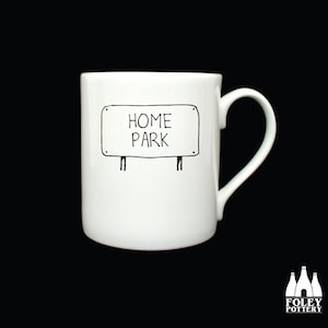 Puede incluir: Taza de cerámica blanca con un dibujo de línea negra de un letrero que dice "Home Park".