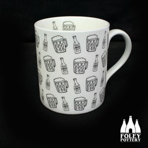 May include: White ceramic mug with a black and white pattern of beer mugs and bottles. The mug has a handle and says "FOLEY POTTERY" on the bottom.