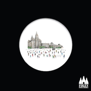 Puede incluir: Un posavasos de cerámica blanca con una ilustración en blanco y negro del Liver Building y personas caminando frente a él. El texto "LIVERPOOL" está en un cartel en la imagen.