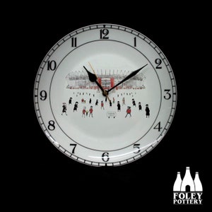 May include: White ceramic clock with black numbers and hands. The clock face features a black and white illustration of a stadium with people walking towards it. The text "KIERAN'S JUBILEE" is visible on the clock face.