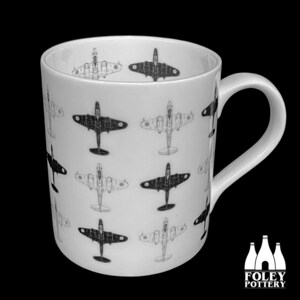 Könnte beinhalten: Eine weiße Keramiktasse mit einem schwarz-weißen Muster aus Vintage-Kampfflugzeugen. Die Tasse hat einen Henkel und die Worte "FOLEY POTTERY" sind auf dem Boden aufgedruckt.