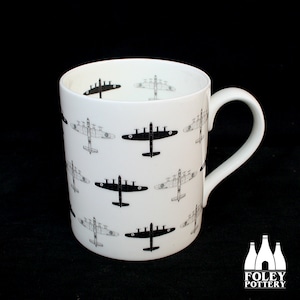 Könnte beinhalten: Weißer Keramikbecher mit einem sich wiederholenden Muster aus schwarzen und grauen Flugzeugillustrationen. Der Becher hat einen gebogenen Henkel und eine zylindrische Form. Das Foley Pottery-Logo ist unten rechts sichtbar.