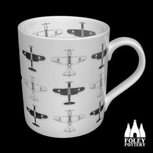 Könnte beinhalten: Weiße Keramiktasse mit einem sich wiederholenden Muster aus Vintage-Flugzeugen in Schwarzweiß. Die Tasse hat einen schwarzen Henkel und die Worte "FOLEY POTTERY" sind auf dem Boden aufgedruckt.