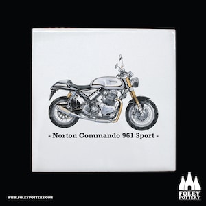 Könnte beinhalten: Eine Illustration eines weißen und schwarzen Norton Commando 961 Sport Motorrads. Das Motorrad hat einen silbernen Tank mit dem Wort "Norton" darauf gedruckt. Der Text "Norton Commando 961 Sport" ist unter dem Motorrad gedruckt.