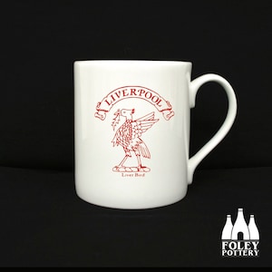 May include: White ceramic mug with a red Liverpool Liver Bird design. The mug has a handle and says "Liverpool" and "Liver Bird" in red.