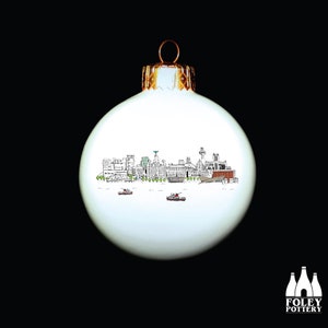 May include: White Christmas ornament with a black and white illustration of the Liverpool skyline. The ornament has a gold top.