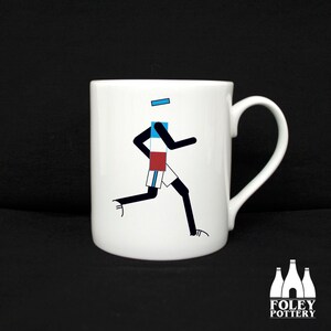 May include: White ceramic mug featuring a black and white illustration of a runner wearing a blue, white and red jersey. The mug has a black handle.