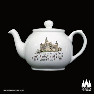Puede incluir: Tetera de cerámica blanca con una ilustración en blanco y negro de la Torre de Londres y muchas personas pequeñas delante de ella.