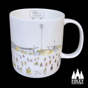 Könnte beinhalten: Weiße Keramiktasse mit einer Schwarzweißillustration eines Stadions mit dem Text "Pirelli Stadium" auf der Vorderseite. Die Tasse hat einen schwarzen Henkel.