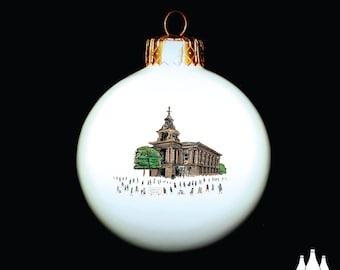 May include: White Christmas ornament with a hand-drawn illustration of a building with a steeple and people in front of it. The ornament has a gold top.
