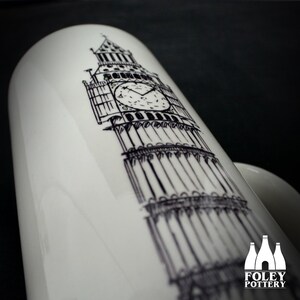 May include: White ceramic mug with a black and white sketch of the Big Ben clock tower. The mug has a curved handle and a glossy finish. The Foley Pottery logo is at the base of the mug.