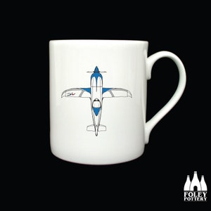 May include: White ceramic mug with a blue and white airplane illustration. The airplane is facing down with the text "3L" on the side.