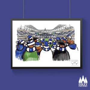 Puede incluir: Una impresión enmarcada que representa a una multitud de espectadores en un estadio de fútbol. La ilustración muestra a los aficionados con gorros y bufandas azules y blancas, con el estadio y el campo de fondo. El letrero dice "White Hart Lane".