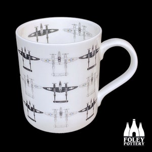 May include: White ceramic mug with a black and white repeating pattern of Lockheed P-38 Lightning fighter planes. The mug has a black handle and the words "FOLEY POTTERY" are printed on the bottom.