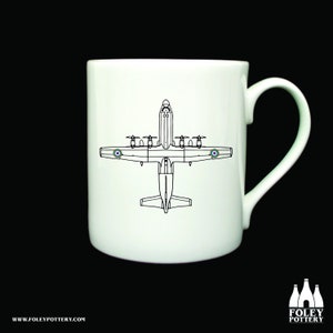 May include: White ceramic mug with a black line drawing of a plane on it. The plane is a British Royal Air Force aircraft with roundels on the wings. The mug has a handle on the right side.