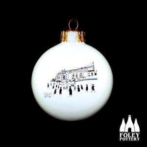May include: White ceramic Christmas bauble featuring a black and blue illustration of a stadium and people walking towards it. The text "Stamford Bridge" is on a small sign in the bottom left corner.