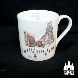 May include: White ceramic mug with a black and white illustration of a coal mine with a sign that reads "Littleton". The illustration includes a tall structure with a pulley system and a group of stick figures in front of the mine.