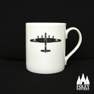 Könnte beinhalten: Eine weiße Keramiktasse mit einer schwarzen Silhouette eines Vintage-Bombers. Die Tasse hat einen Henkel auf der rechten Seite. Die Tasse steht auf einem schwarzen Hintergrund. Der Text "FOLEY POTTERY" ist am unteren Rand des Bildes sichtbar.