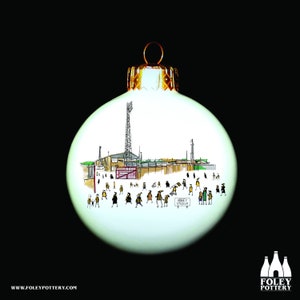 May include: A white Christmas bauble with a hand-drawn illustration of a football stadium and fans. The bauble features the text "Abbey Stadium".