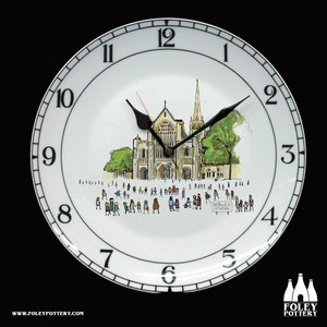 May include: A white ceramic clock plate with black numbers and hands. The plate features a black and white illustration of Norwich Cathedral with people walking around it. The text "NORWICH CATHEDRAL" is printed on a sign in the illustration.